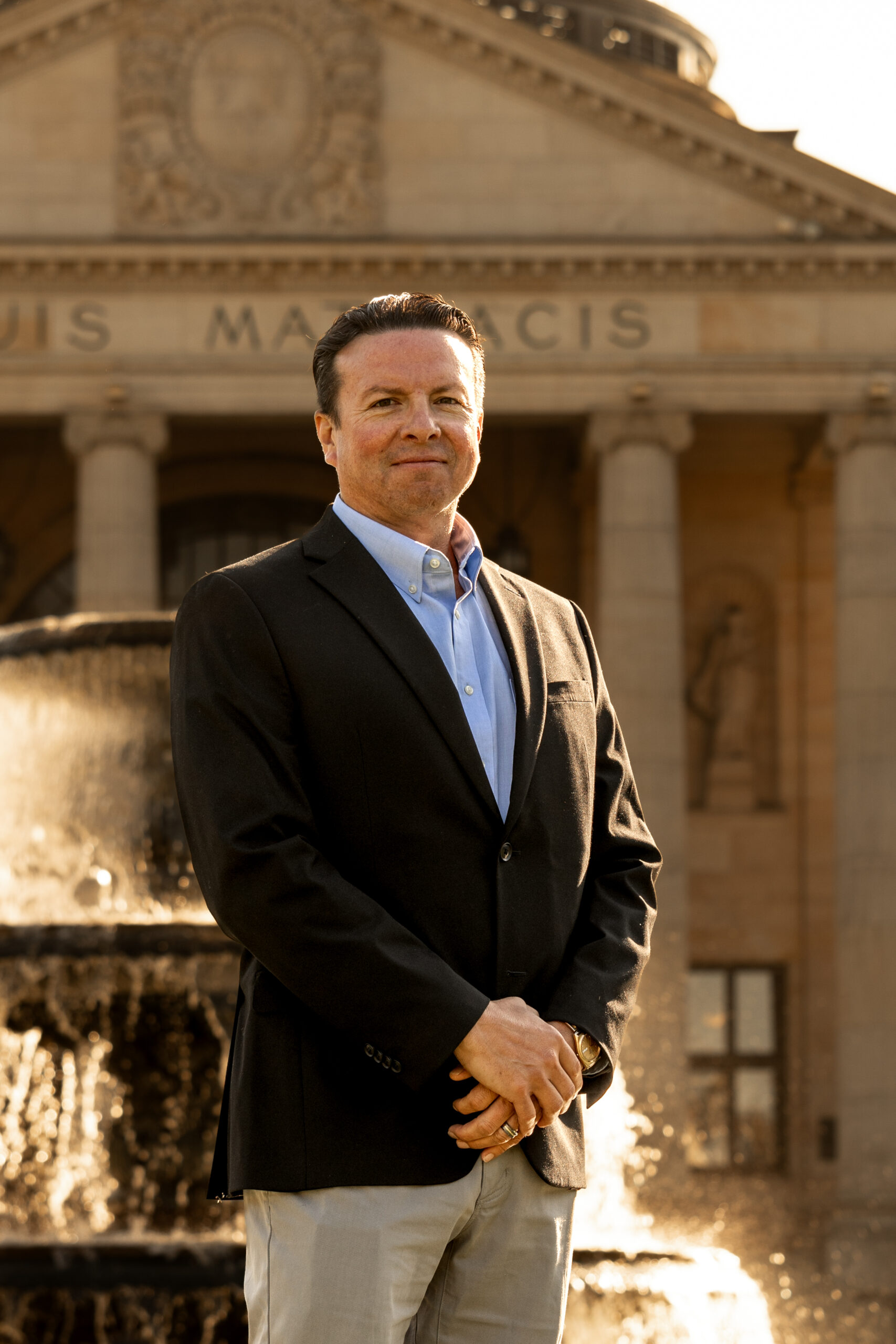 Andre Le Blanc in dark blazer posing in front of fountain