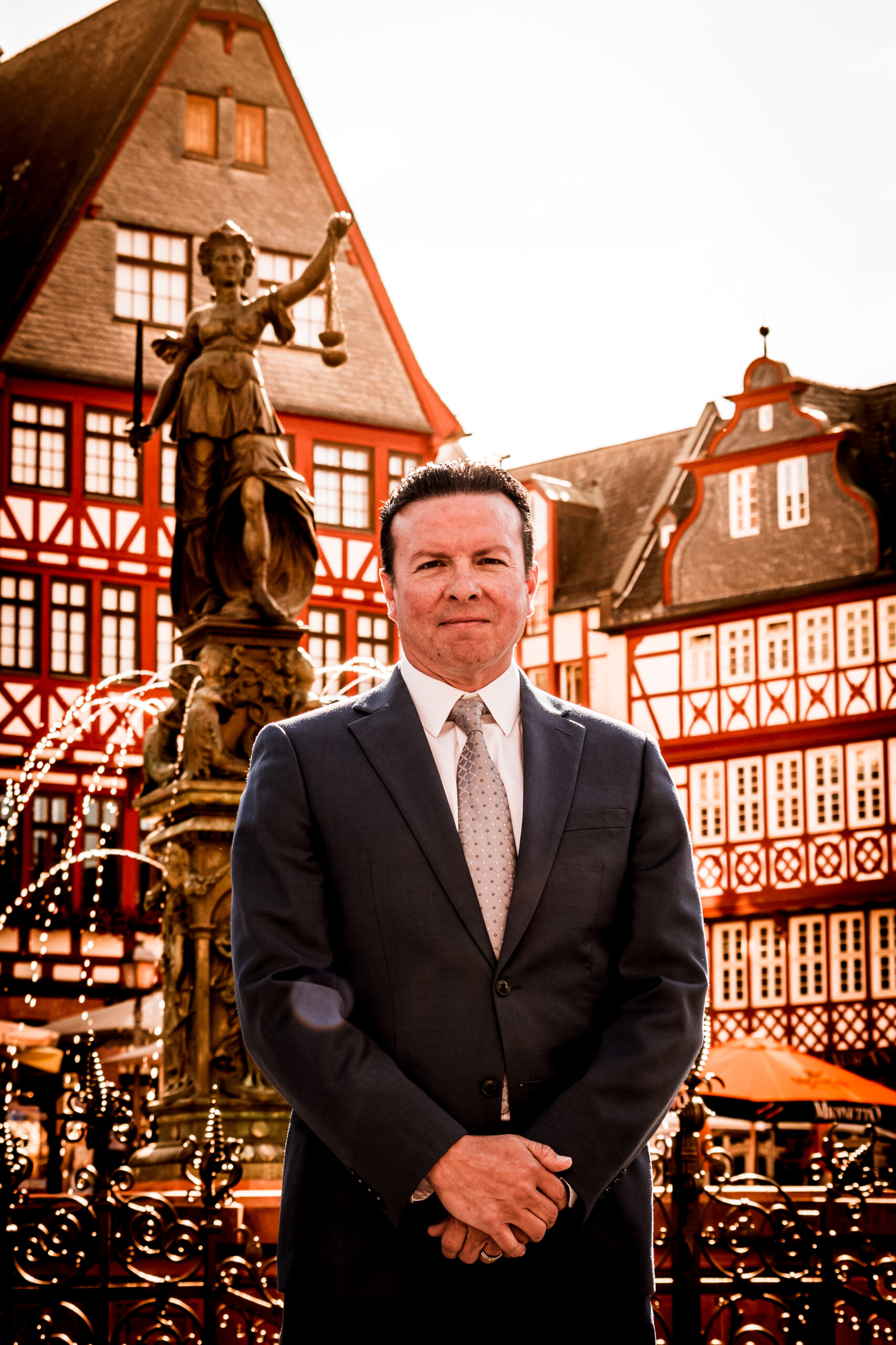 Andre Le Blanc in suit standing before fountain in Frankfurt
