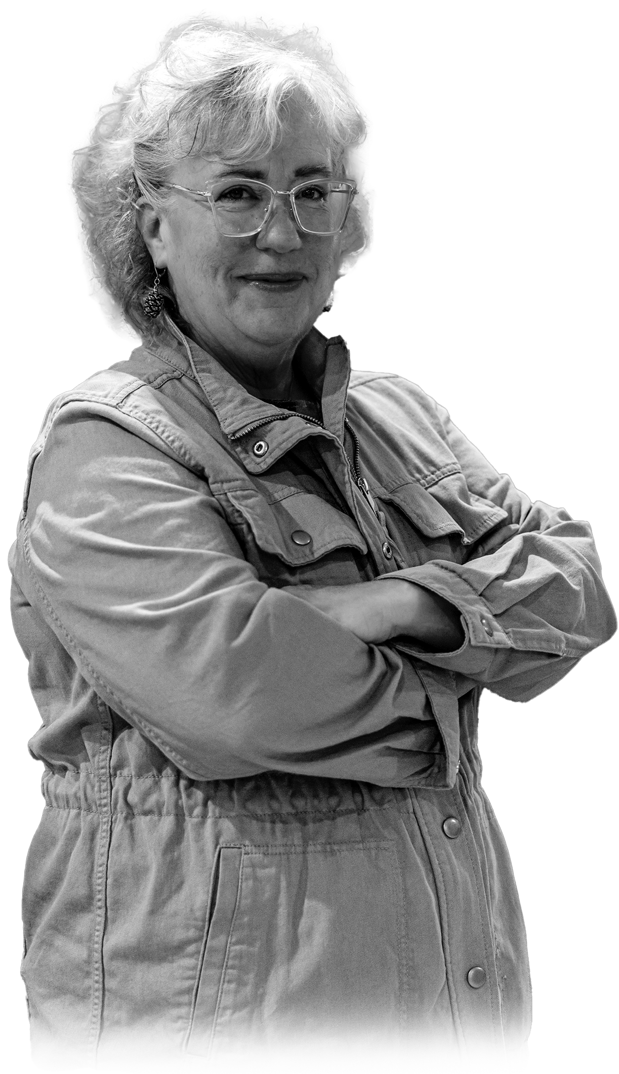 Genie Hughes standing with arms crossed wearing glasses and jacket in black and white portrait