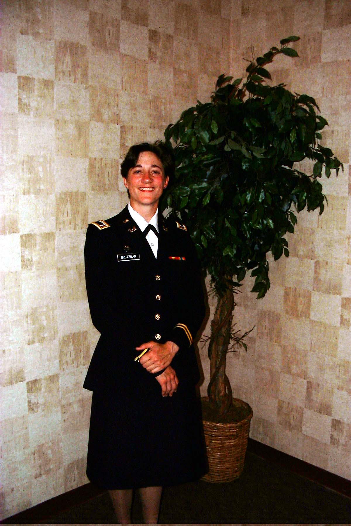 Mary Ritzmann in First Lieutenant JAG uniform standing by a plant
