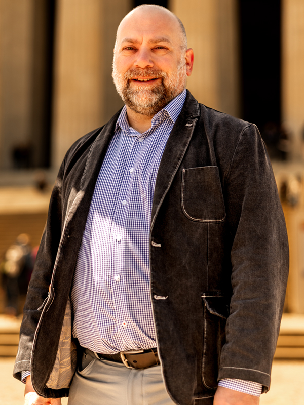 Military attorney Matthew Krause standing in black jacket and checkered shirt