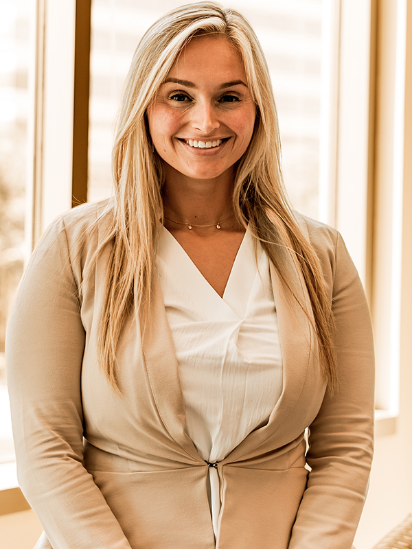 Military attorney Stefany Garrick standing indoors, wearing light beige suit jacket and white blouse.