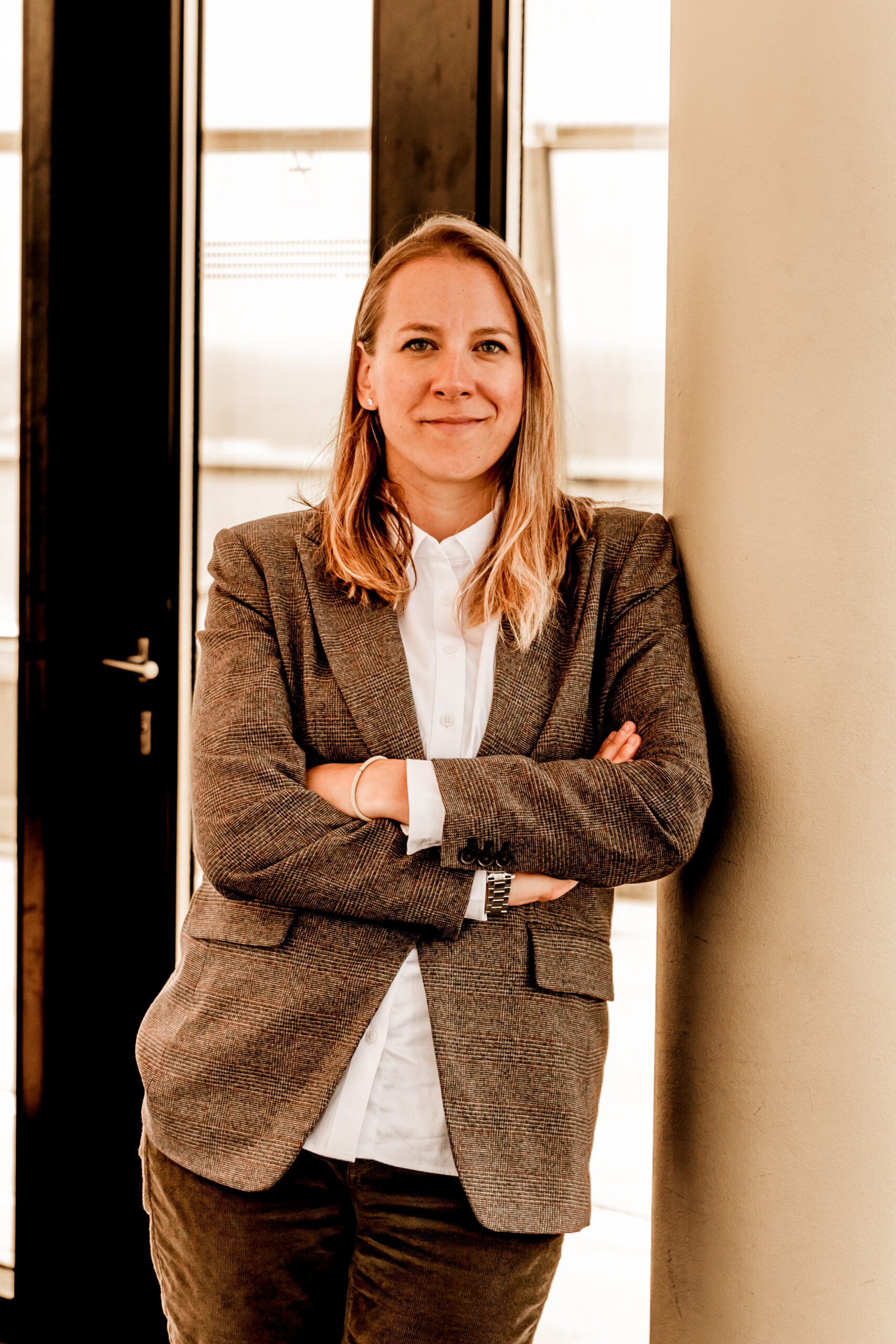Natalia Helmsing standing with arms crossed beside a column in business jacket