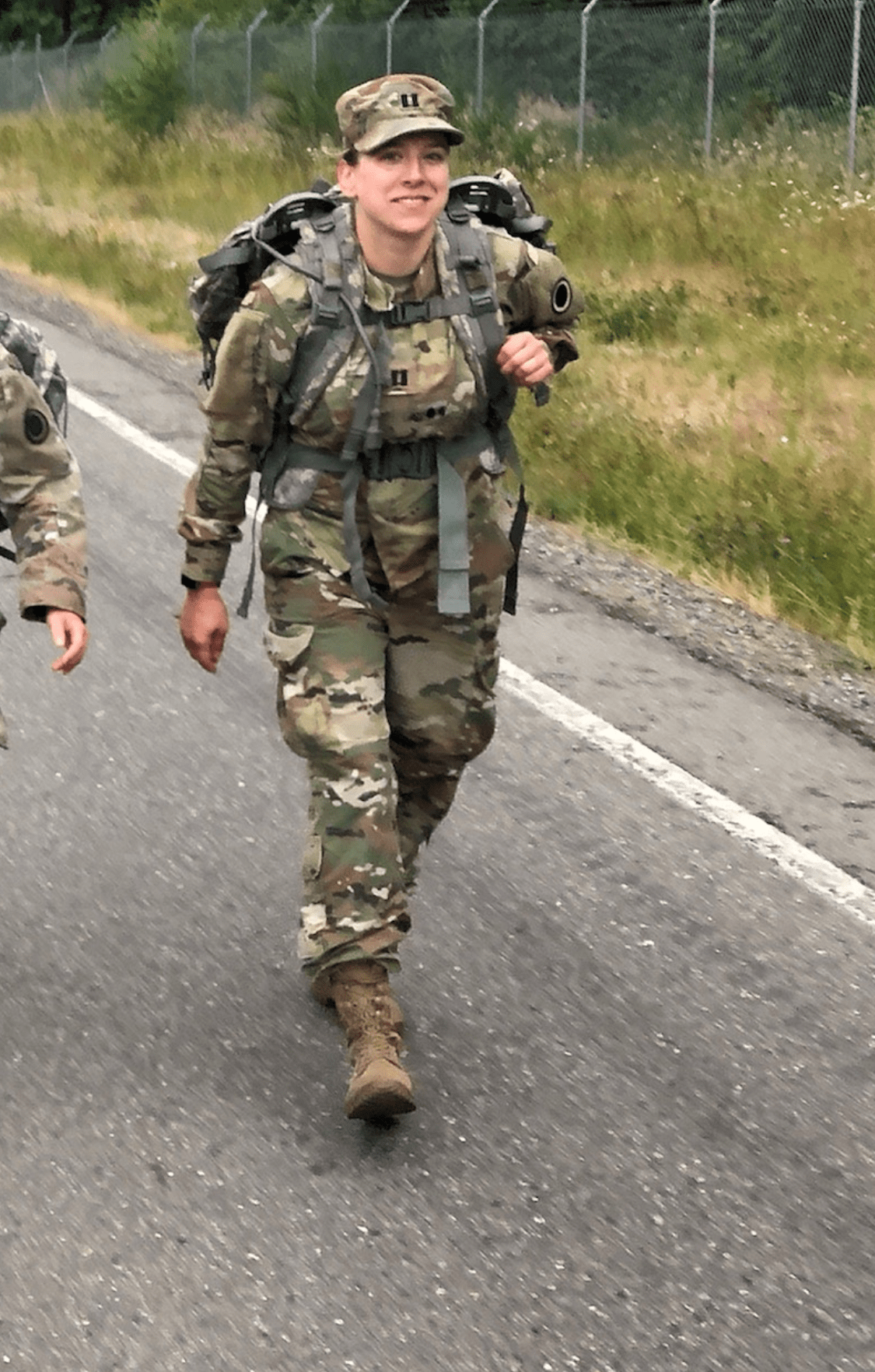 Natalia Helmsing participating in a military ruck march on a roadside