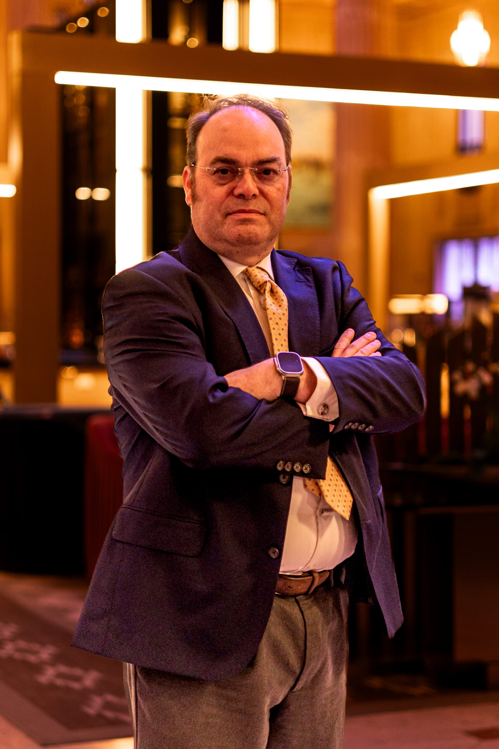 Robert Newark standing in a blue suit in a brightly lit lobby