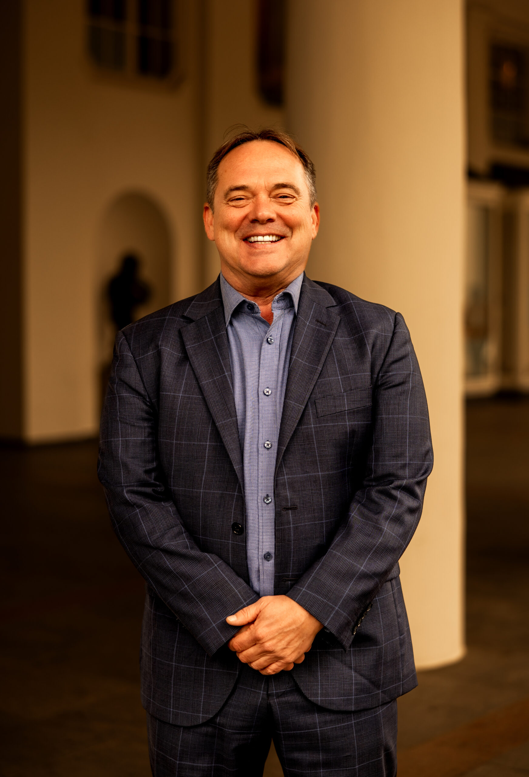 Scott Brokaw standing with hands clasped in building with columns