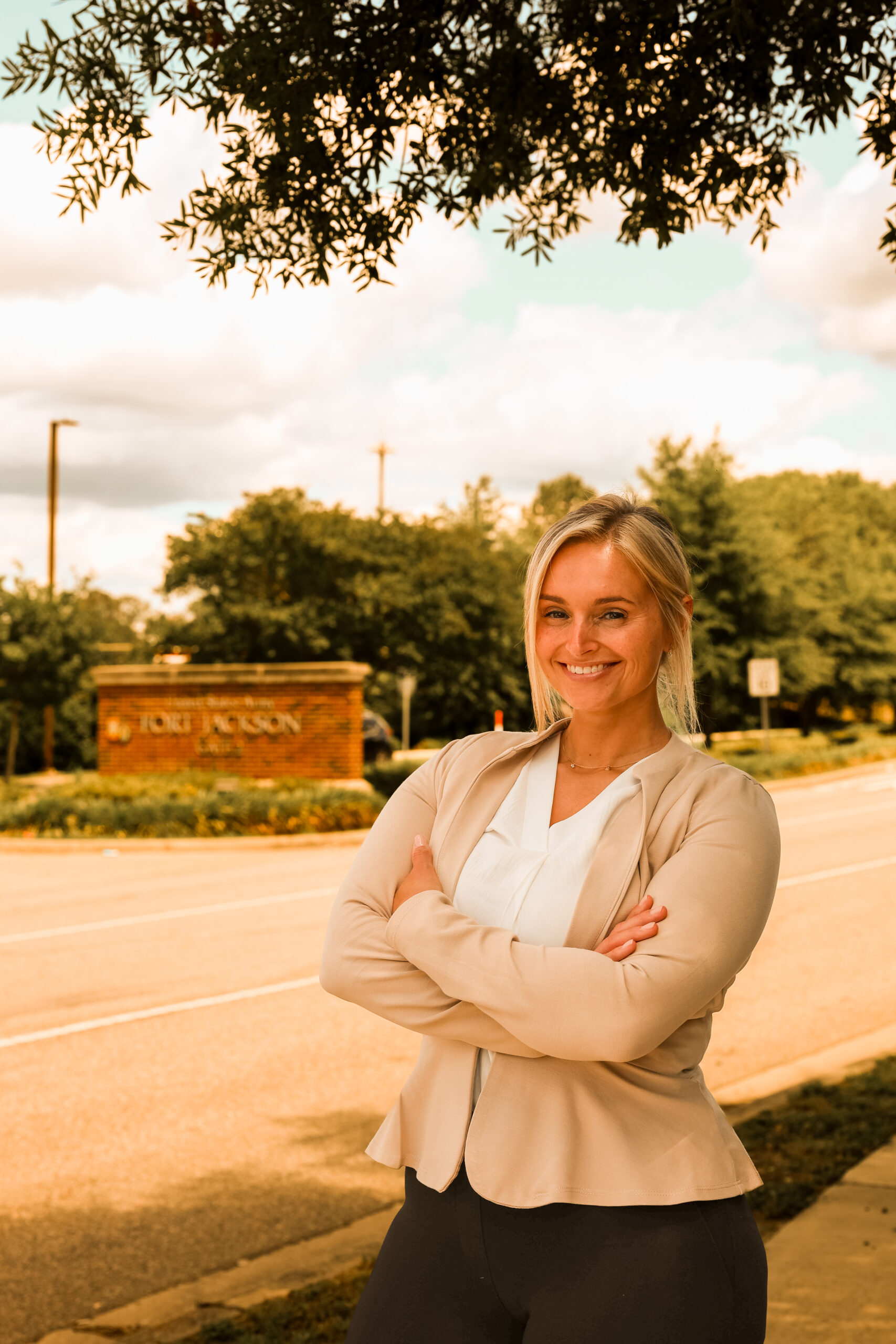 Stefany Garrick standing outdoors with arms crossed near entrance sign