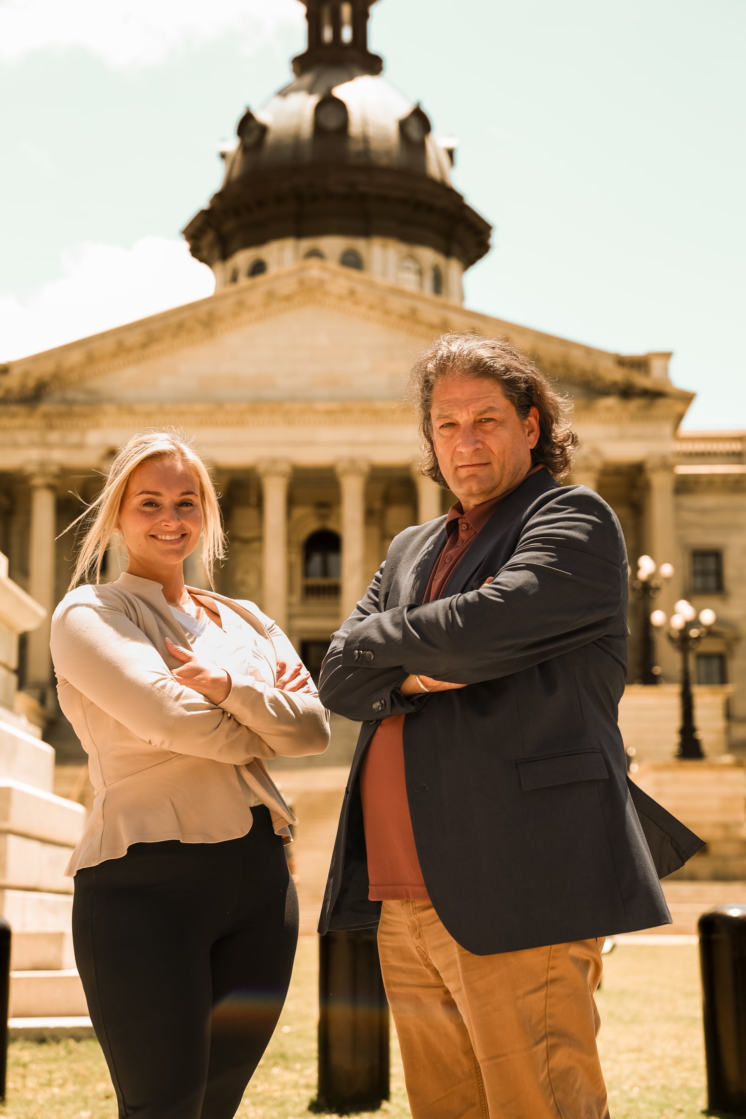 Stefany Garrick and Will M. Helixon standing with arms crossed in front of a historic building