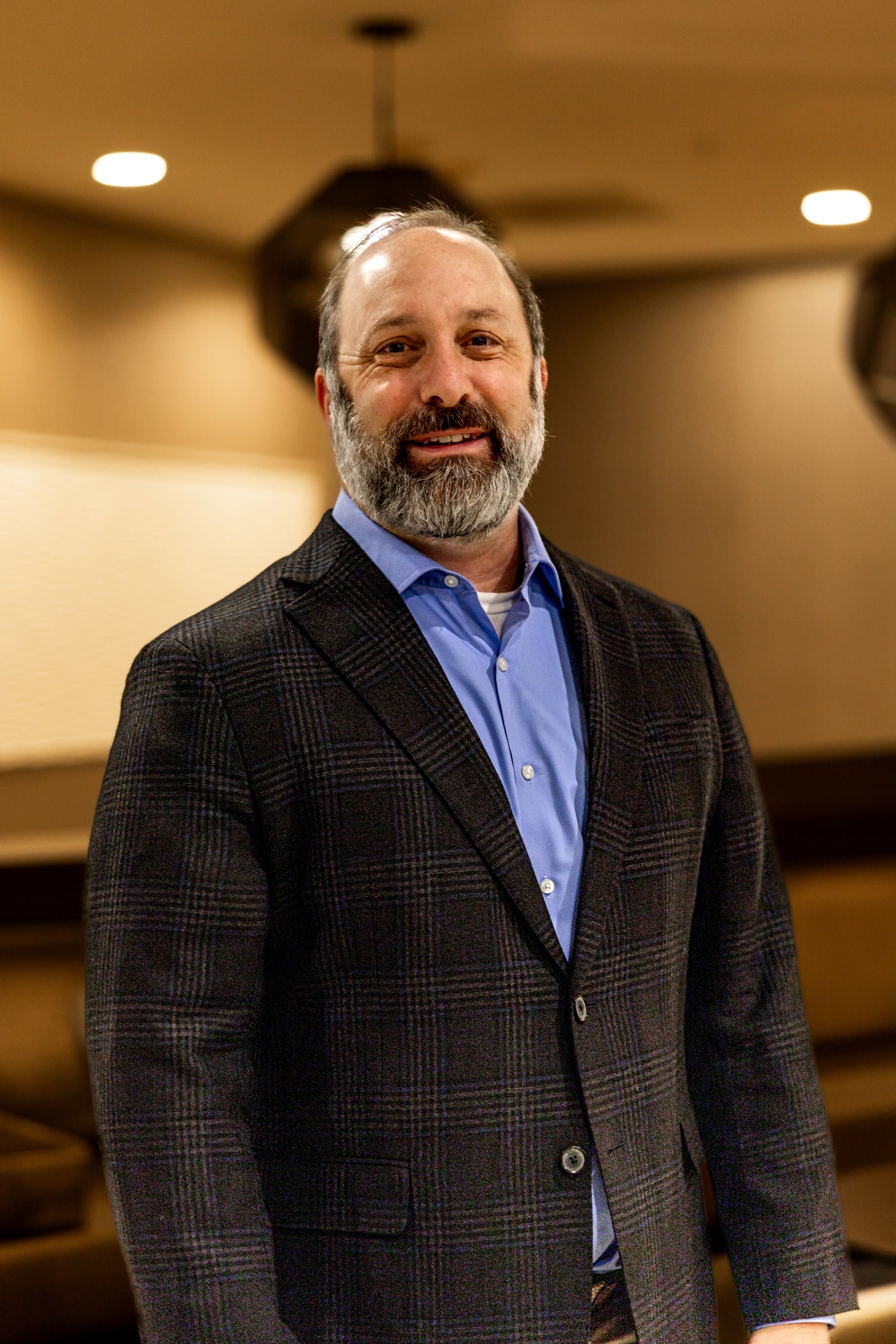 Treb Courie standing in a modern lounge wearing a plaid jacket