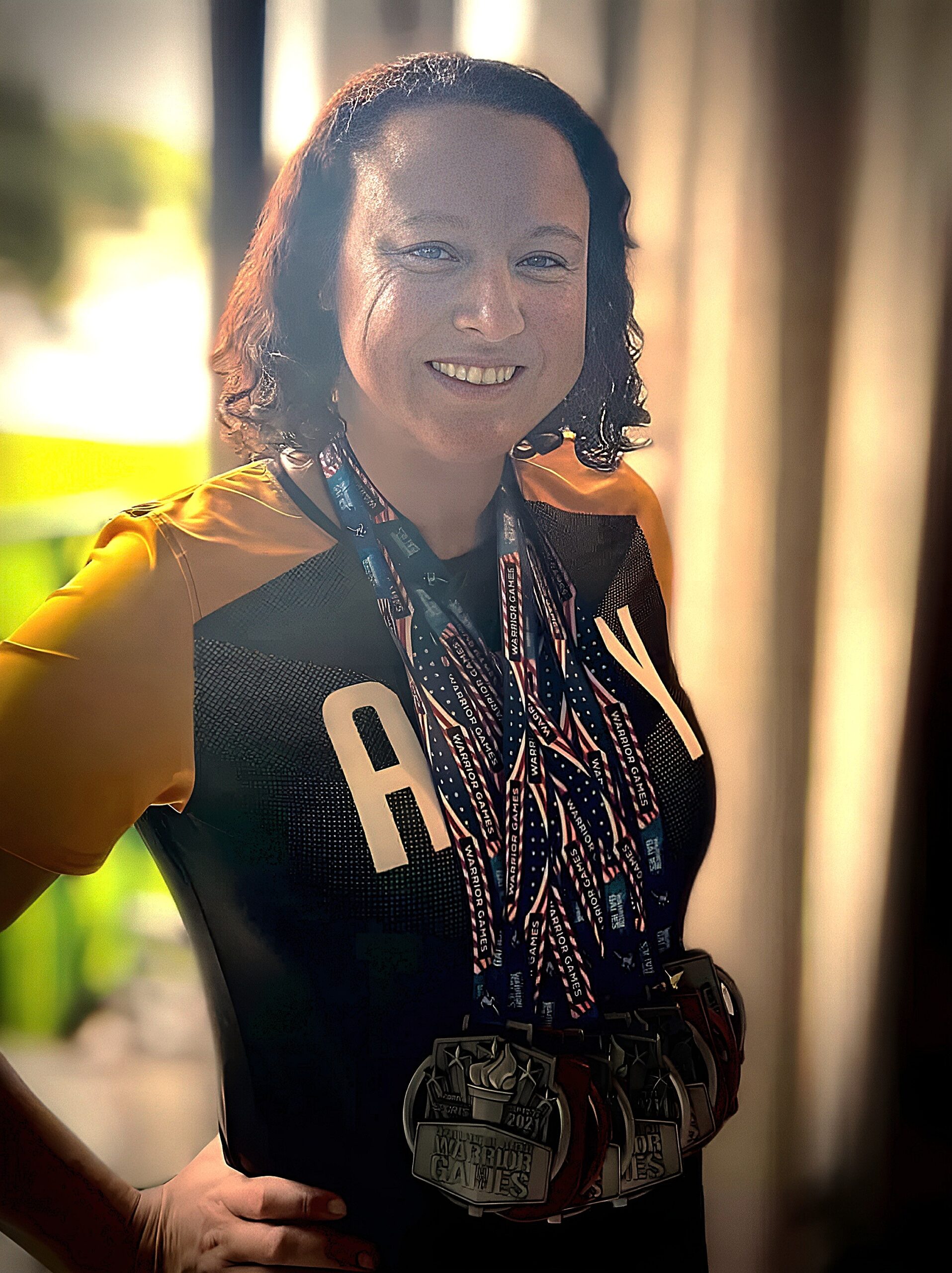 Victoria Camire wearing Army team shirt with multiple Warrior Games medals