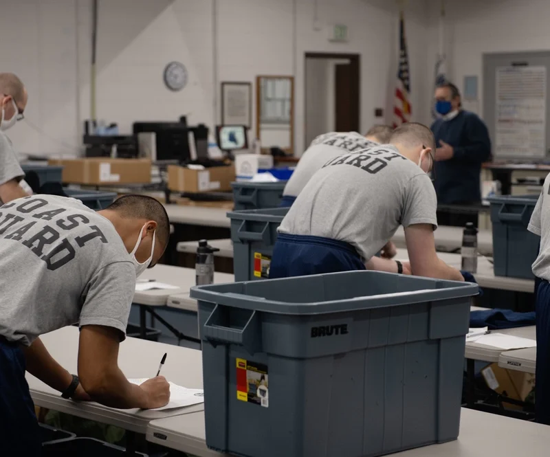 Coast Guard recruits from company T-199 sign uniform-issue paperwork at Training Center Cape May in January 2021