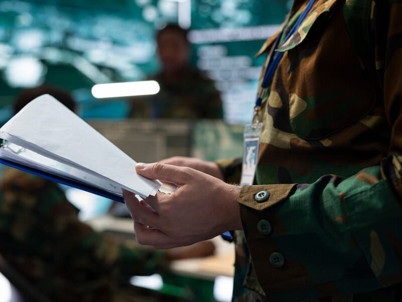 Uniformed Service member turning pages in a case file binder while reviewing military sexual assault case dispositions