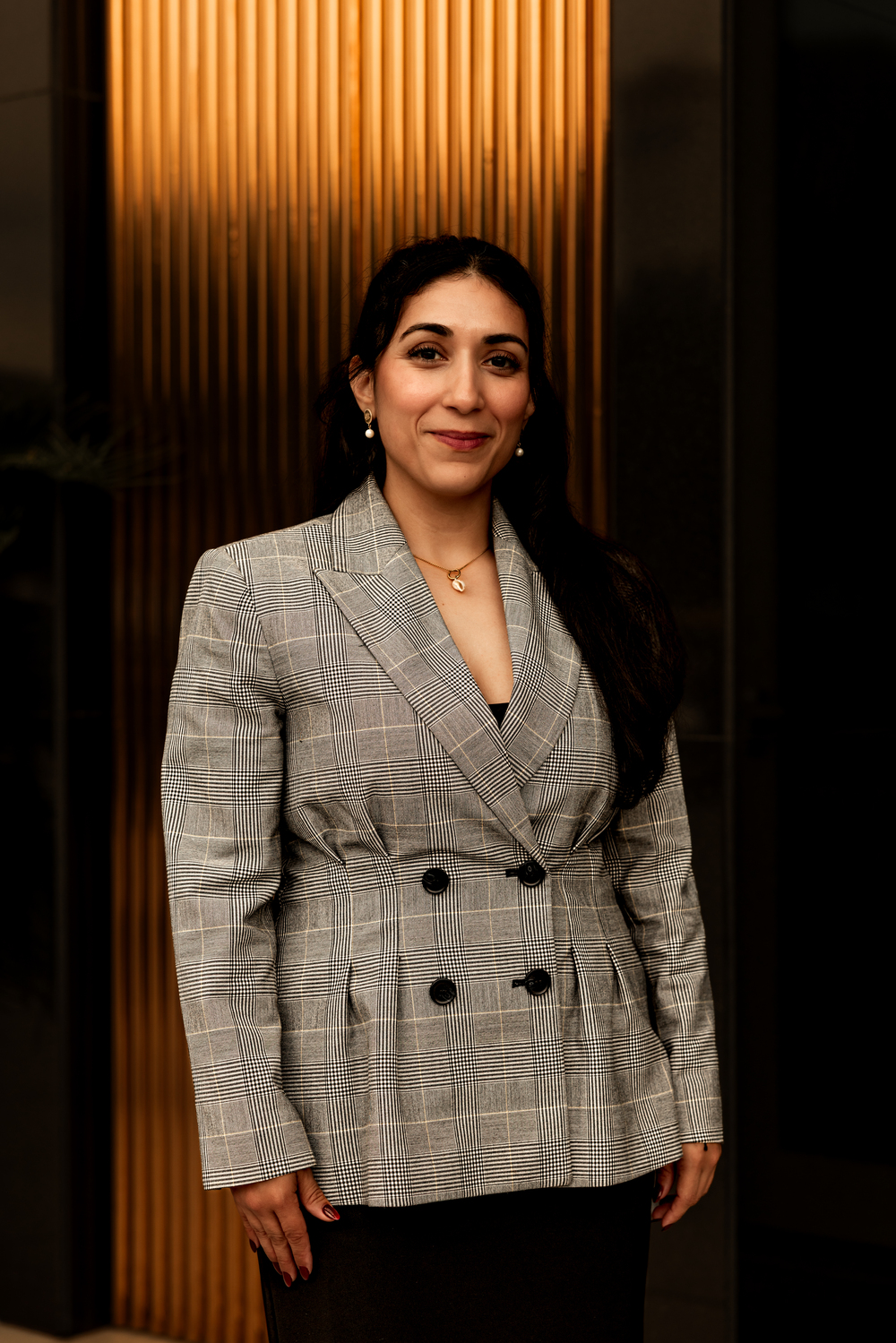 Military lawyer Linda Aguilera standing in a grey plaid blazer, smiling at the camera