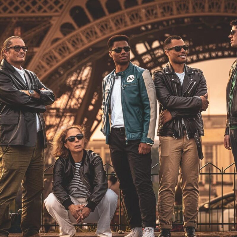 Will Helixon and his family in leather jackets and sunglasses pose in front of the Eiffel Tower in Paris at sunset